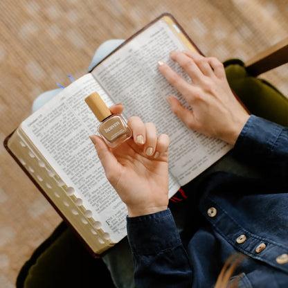 Person holding a bottle of Heaven Nail Polish over a Bible.