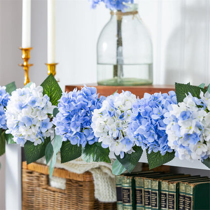 Hydrangea Haven decorative garland of blue and white hydrangeas on a surface with books and a basket in the background.