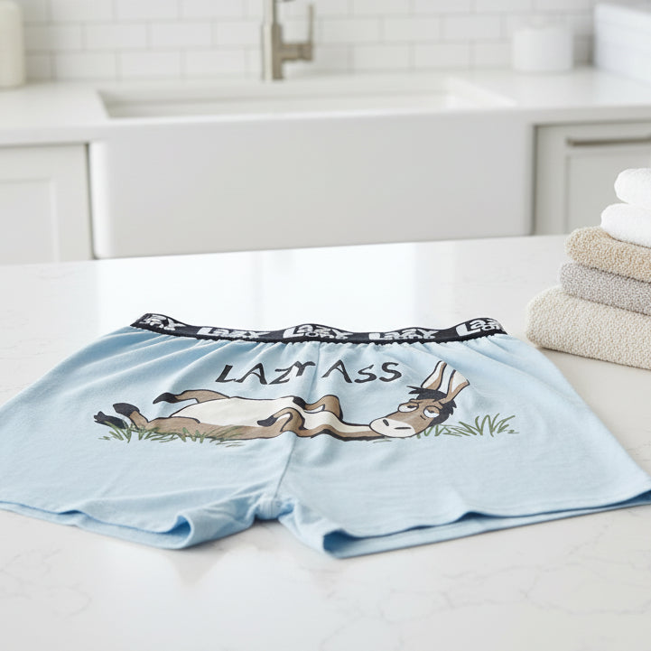 Light blue boxer shorts with a cartoon donkey and 'Lazy Ass' text, featuring the brand 'Lazy One' - laying on a counter
