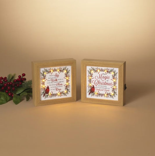 Two framed Christmas-themed signs with decorative lights on a beige background.