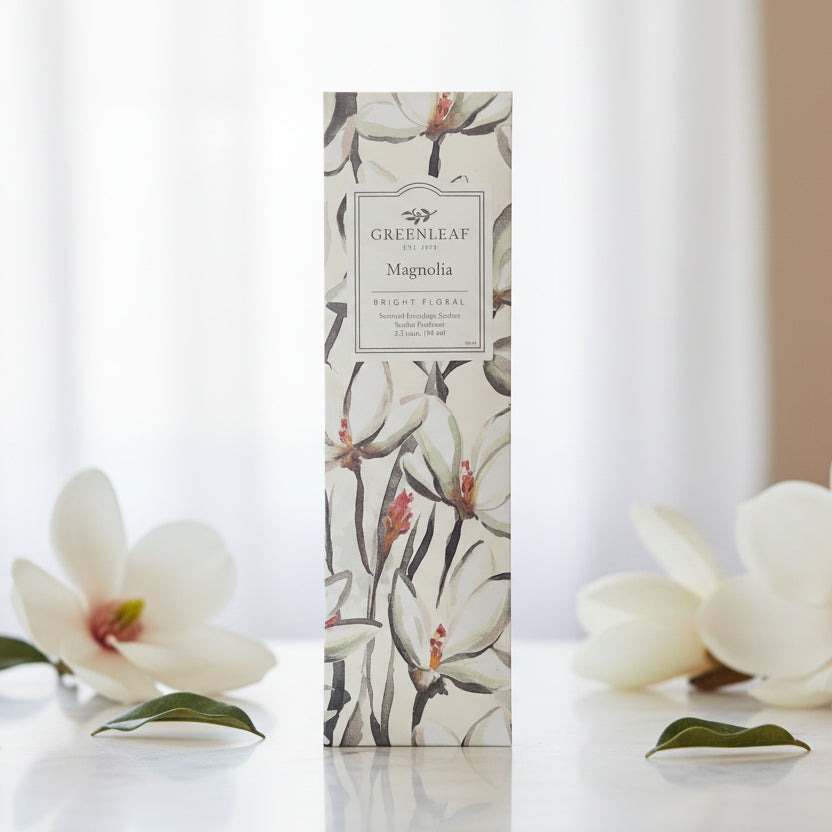 Greenleaf Magnolia slim sachet on a table with magnolia flowers.
