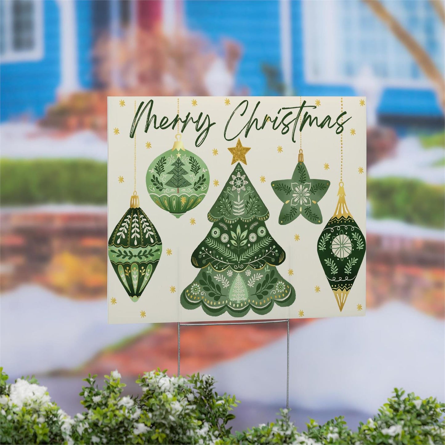 Christmas-themed yard sign with green trees and ornaments in front of a blurred house background.