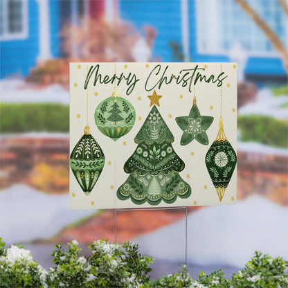 Christmas-themed yard sign with green trees and ornaments in front of a blurred house background.