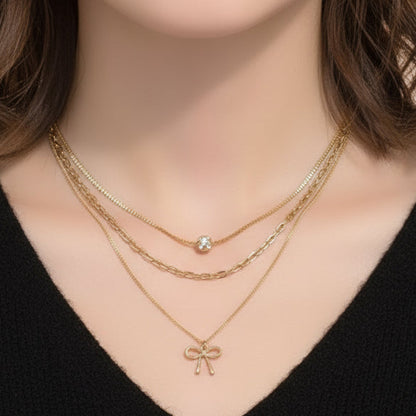 Gold necklace with bow and round charm on a woman