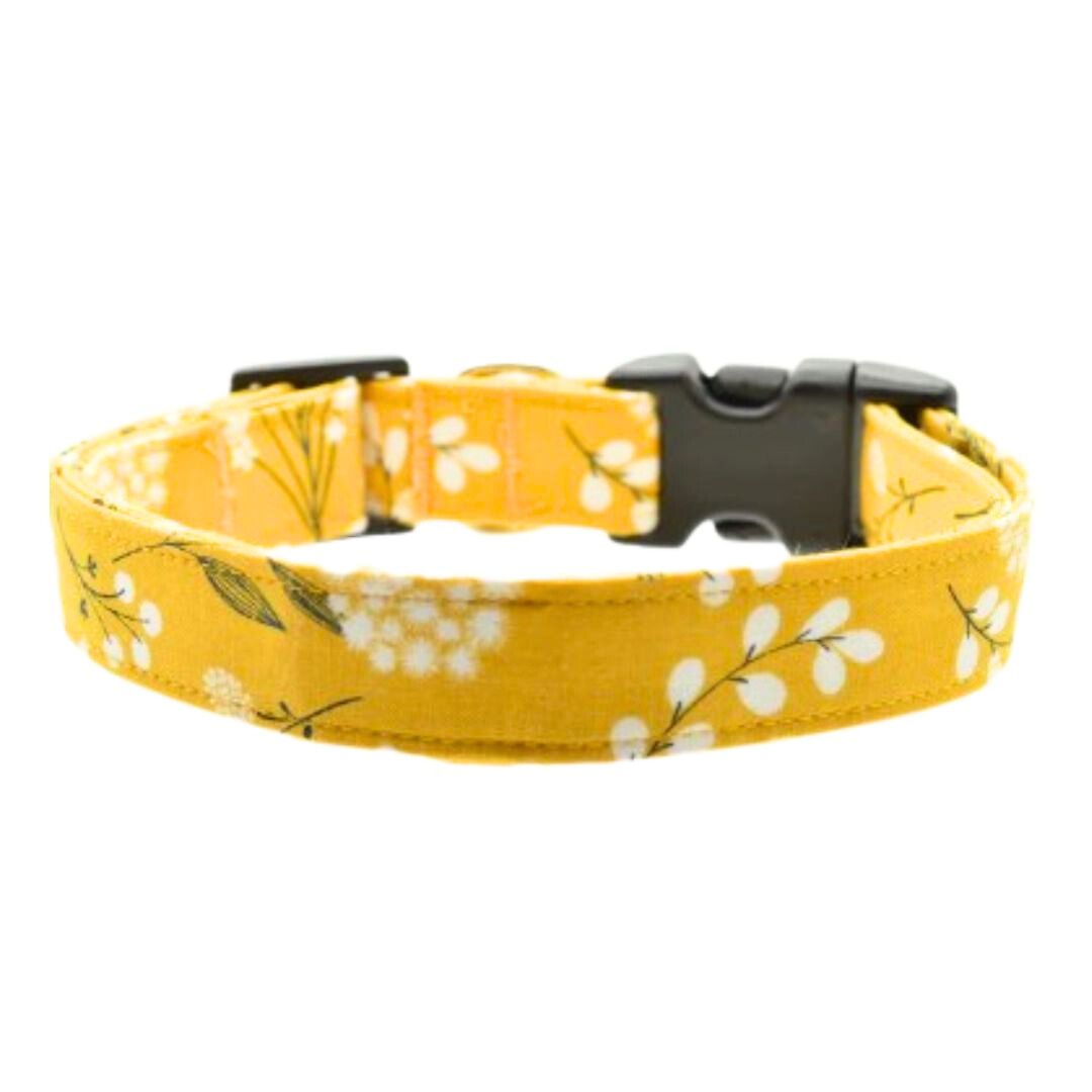 Yellow floral-patterned dog collar with a black buckle on a white background