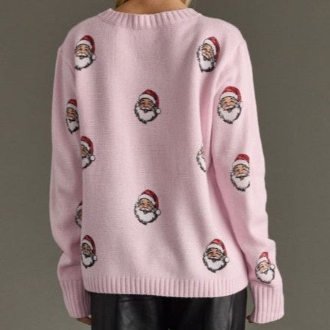 Pink sweater with embroidered Santa Claus faces on a plain background