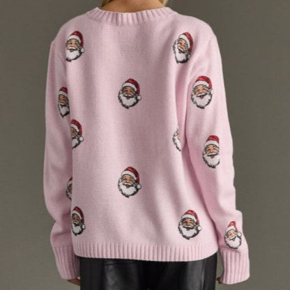 Pink sweater with embroidered Santa Claus faces on a plain background