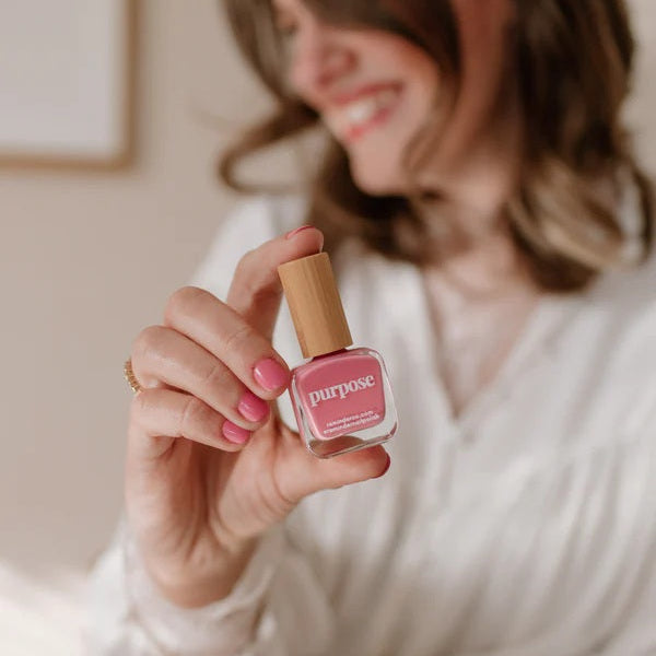 Woman holding a bottle of Reminder Nail Polish in Purpose Honeysuckle Pink