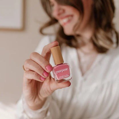 Woman holding a bottle of Reminder Nail Polish in Purpose Honeysuckle Pink