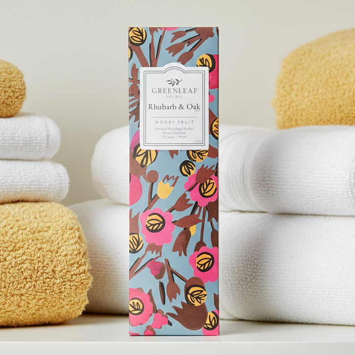 Greenleaf Rhubarb & Oak slim sachet on a shelf with white and golden yellow towels.