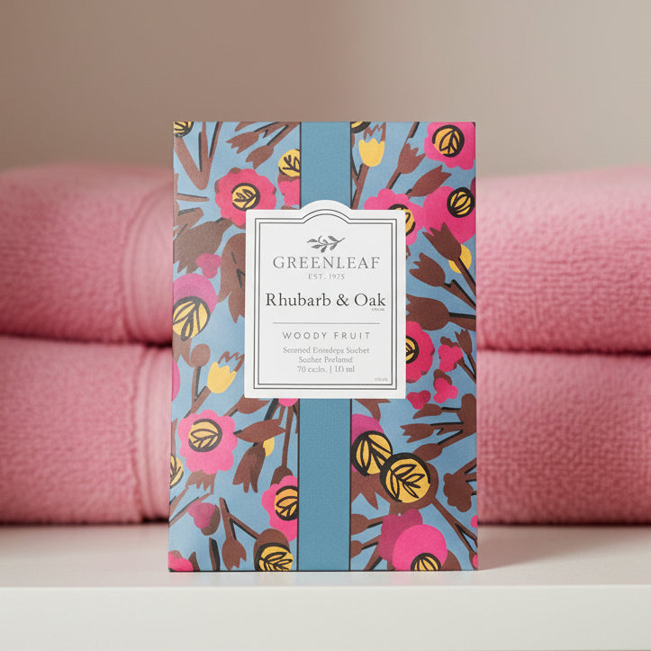 Greenleaf Rhubarb & Oak sachet on a shelf with pink towels behind it,