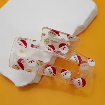 Clear hair clip with Santa design on a yellow background