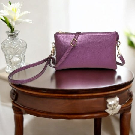 SHIIMERY PURPLE HAND BAG ON A BROWN TABLE 