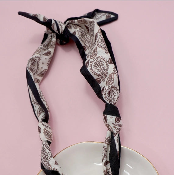 Patterned scarf with a heart-shaped pendant on a white plate against a pink background