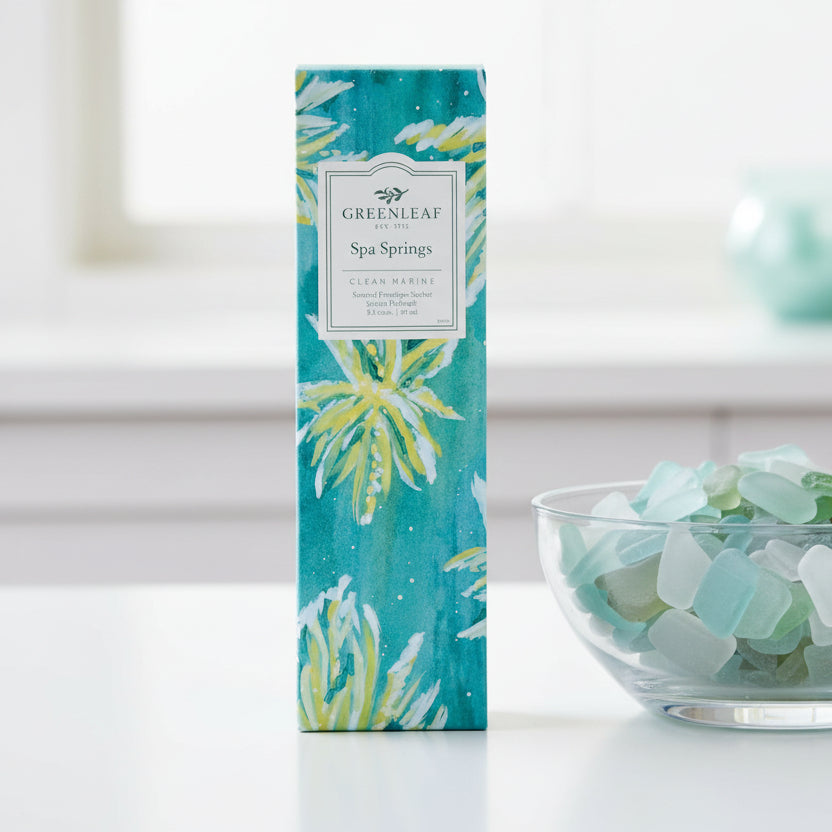 Greenleaf Spa Sprigs slim sachet on a white counter with a bowl of blue and green sea glass