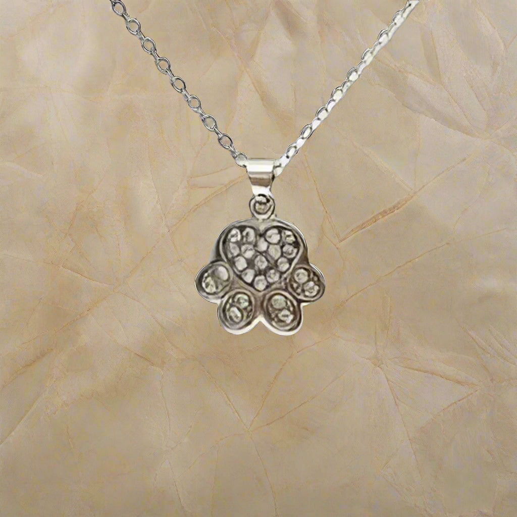 Silver Hamsa hand pendant necklace on a beige textured background