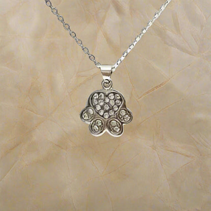 Silver Hamsa hand pendant necklace on a beige textured background