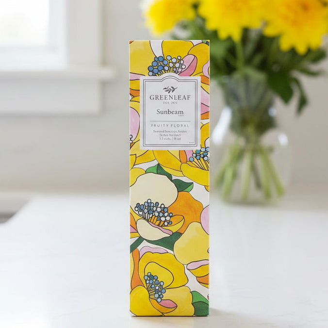 Greenleaf Sunbeam slim sachet on a kitchen counter with a vase of yellow flowers behind it.