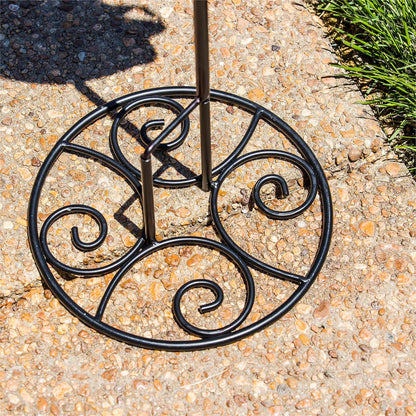 Elegant Swirl Flag Stand Base made of black metal on a pebbled surface.