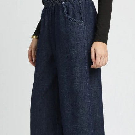 Dark blue wide-leg jeans worn by a person on a light gray background
