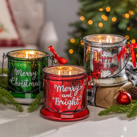 Decorative candles with 'Merry Christmas' and 'Happy Holidays' text in front of a Christmas tree.