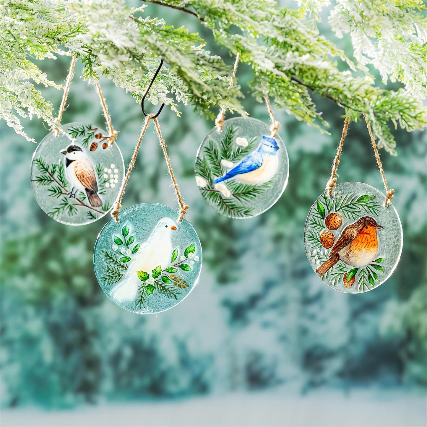 Decorative bird suncatchers hanging from a branch with a blurred green background