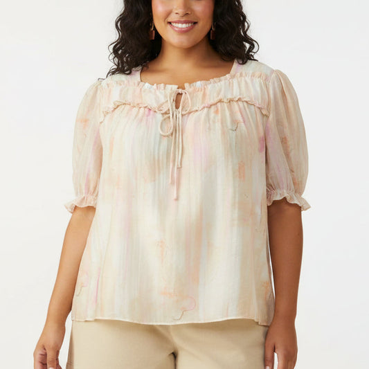 Woman wearing a light-colored blouse with ruffled details and shorts on a white background