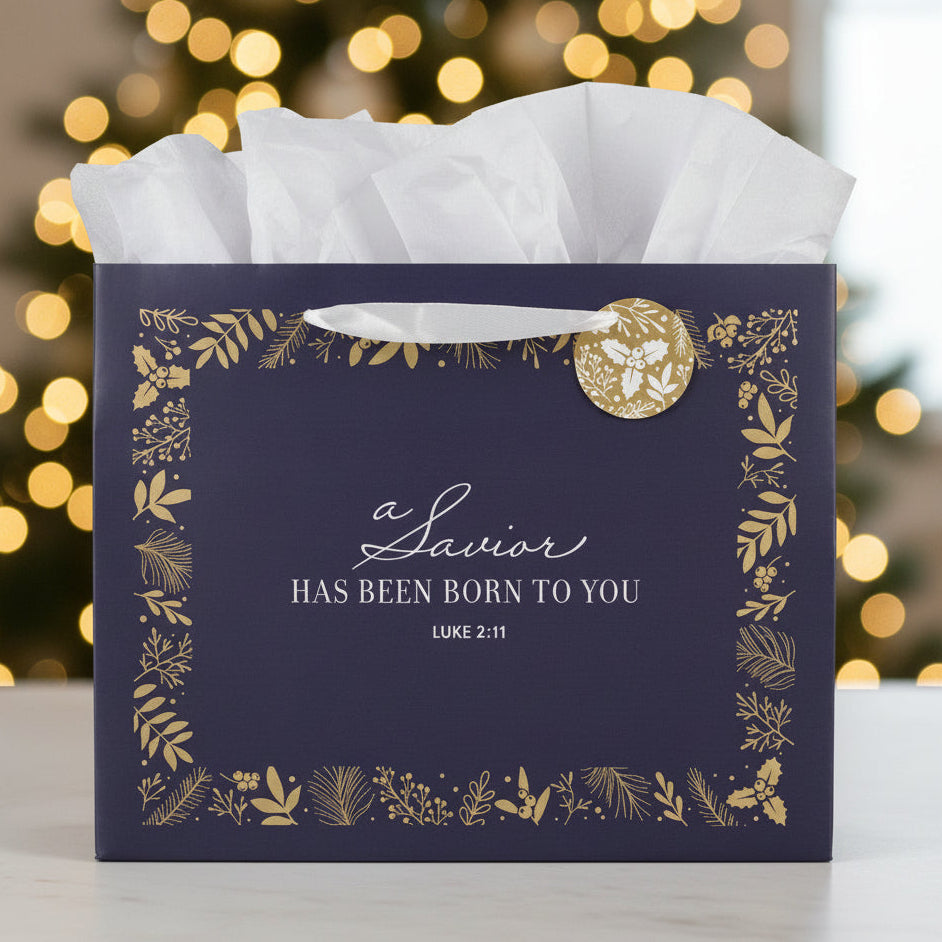 Navy gift box with gold accents and Christmas-themed text against a blurred festive background