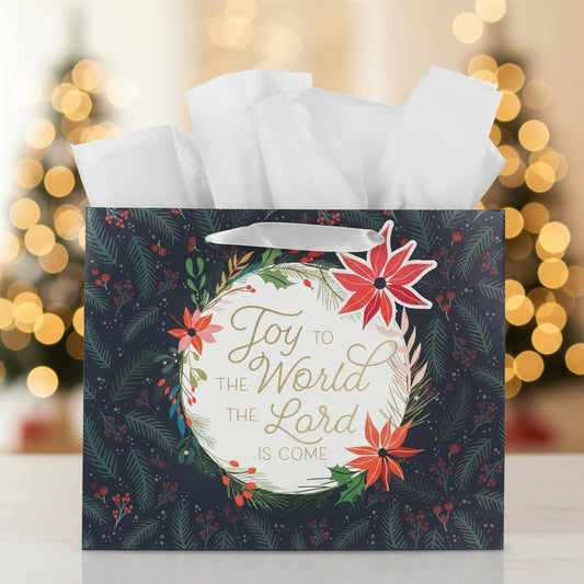 Christmas-themed gift bag with floral design and text 'Joy to the World the Lord is Come' against a blurred festive background.