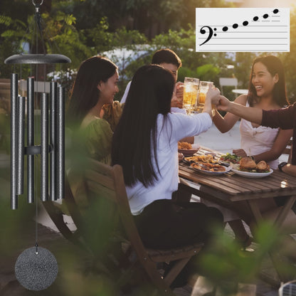 people sitting at outdoor table with meal and wind chimes in foreground